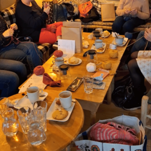 Personnes tricotant autour d'un goûter lors d'un atelier à Pause Madeleine